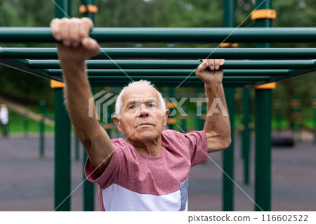 Old climbing on horizontal ladder outdoors Old climbing on horizontal ladder outdoors 116602522