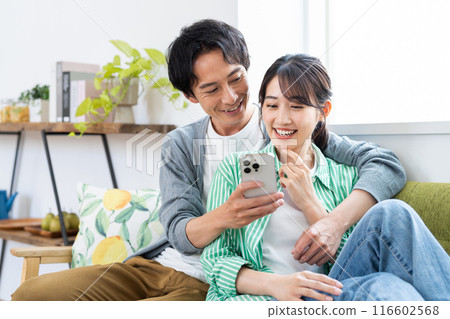 Young couple looking at a smartphone in the living room Young couple looking at a smartphone in the living room 116602568