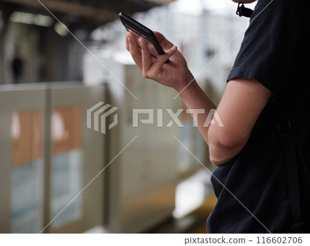 夏天,一名年輕人在月台上一邊等火車,一邊看著智慧型手機 夏天,一名年輕人在月台上一邊等火車,一邊看著智慧型手機 116602706