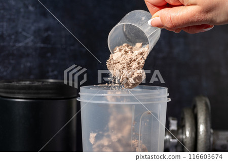 pouring chocolate protein powder in a shaker. Food supplements. Dark background. Bodybuilding, fitness, gym. 116603674