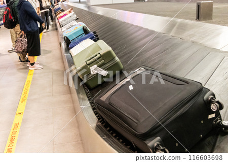 Passengers waiting for baggage at airport conveyor belt carousel system 116603698