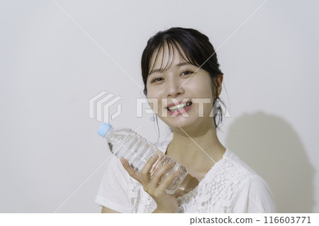 Portrait of a young woman holding a plastic bottle of water on a white background Portrait of a young woman holding a plastic bottle of water on a white background 116603771