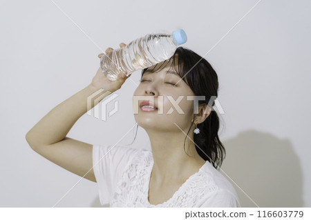 Portrait of a young woman holding a plastic bottle of water on a white background Portrait of a young woman holding a plastic bottle of water on a white background 116603779