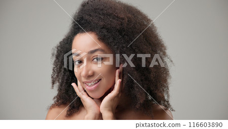 Beauty and healthcare concept - beautiful African American woman with curly afro hairstyle and clean, healthy skin looking in virtual mirror, touching hair, face and smiling Beauty and healthcare concept - beautiful African American woman with curly afro hairstyle and clean, healthy skin looking in virtual mirror, touching hair, face and smiling 116603890