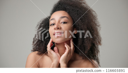 Beauty and healthcare concept - beautiful African American woman with curly afro hairstyle and clean, healthy skin looking in virtual mirror, touching hair, face and smiling 116603891