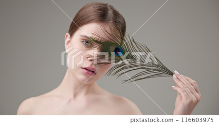 Beauty, health, cosmetics, anti-aging therapy and skin care concept - young beautiful brunette Caucasian woman holding a colorful peacock feather, concept of tenderness, softness and lightness Beauty, health, cosmetics, anti-aging therapy and skin care concept - young beautiful brunette Caucasian woman holding a colorful peacock feather, concept of tenderness, softness and lightness 116603975