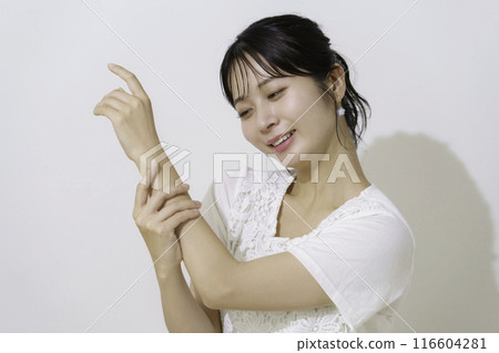 Young woman applying sunscreen to her arm against white background Young woman applying sunscreen to her arm against white background 116604281