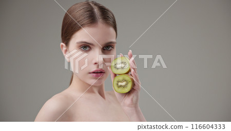 Beauty, health, cosmetics, anti-aging therapy and skin care concept - young beautiful brunette Caucasian woman holding half a kiwi in her hands, concept of vitamins, freshness, fruit power Beauty, health, cosmetics, anti-aging therapy and skin care concept - young beautiful brunette Caucasian woman holding half a kiwi in her hands, concept of vitamins, freshness, fruit power 116604333