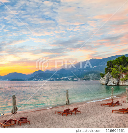 Captivating sunset at beach with chaise lounges and umbrellas in Sveti Stefan near Budva. 116604661