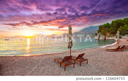 Captivating sunset at beach with chaise lounges and umbrellas in Sveti Stefan near Budva. 116604735