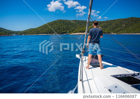 Young man captain on the yacht looking through binoculars during sailing boat. Travel and active life. Yachting Young man captain on the yacht looking through binoculars during sailing boat. Travel and active life. Yachting 116606087