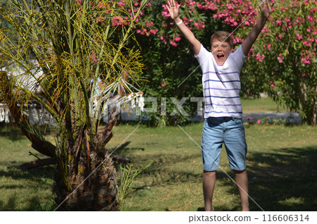 Close up of a young handsome positive curly boy with a smiling face wearing casual whit t-shirt looking at camera. Close up of a young handsome positive curly boy with a smiling face wearing casual whit t-shirt looking at camera. 116606314