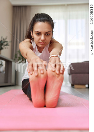Sporty Caucasian woman worm up by stretching her body on pink exercise mat at home 116606516