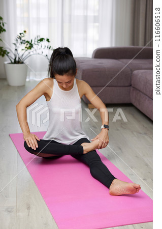 Sporty Caucasian woman worm up by stretching her leg on pink exercise mat at home 116606518