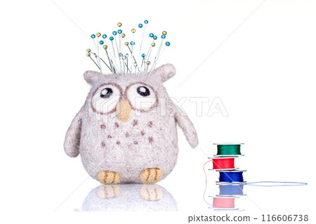 small pillow for needles in the form of an owl with threads on a white background 116606738