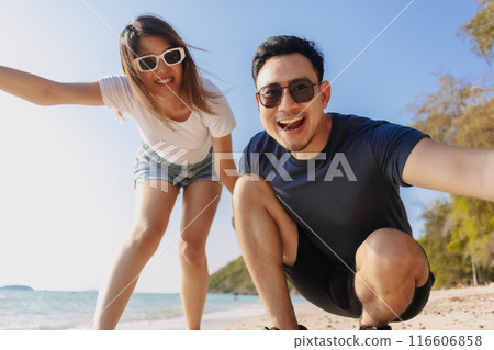 Playful couple lovers taking photo together at the beach, low angle. 116606858