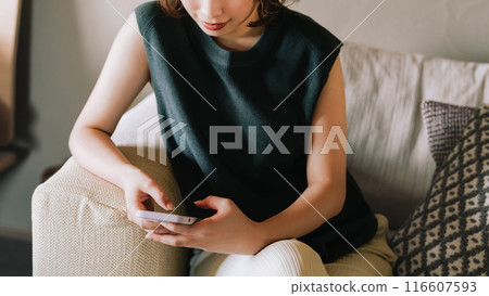 一個微笑的日本女人在沙發上使用智能手機 一個微笑的日本女人在沙發上使用智能手機 116607593
