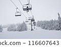 Ski Lift in Winter Wonderland: Skiers Ascend Snow-Covered Mountain Amidst Frosty Trees and Serene Winter Landscape 116607643