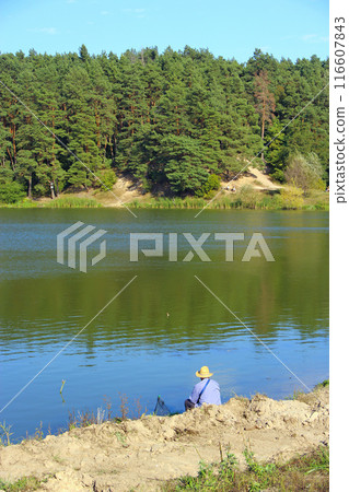 Fisherman standing on riverside and trying to catch fish. Male hobby. Recreation Fisherman standing on riverside and trying to catch fish. Male hobby. Recreation 116607843