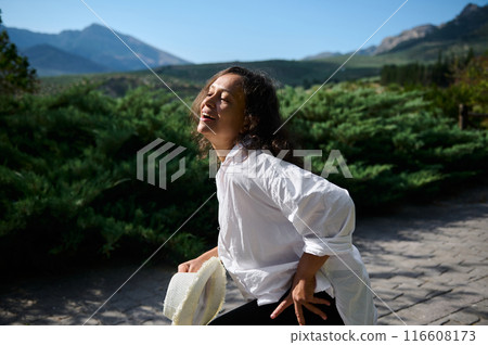 Smiling woman in white shirt enjoying a sunny day in the mountains 116608173
