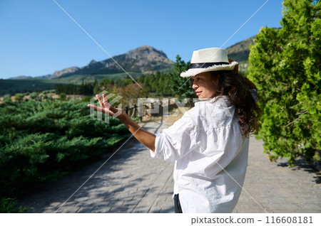 Woman in white shirt and hat exploring nature on a sunny day 116608181