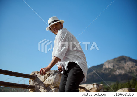 Young man in white shirt and hat enjoying a sunny day outdoors in the mountains 116608190