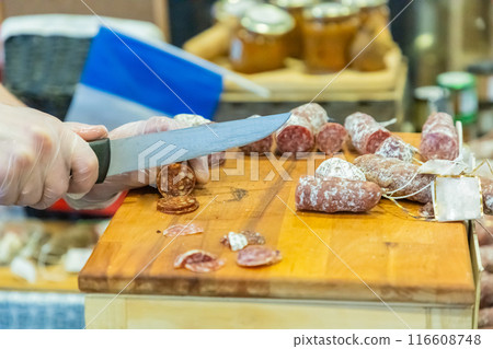 unrecognizable female hands cut a piece of salami 116608748