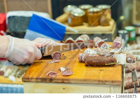 unrecognizable female hands cut a piece of salami 116608875