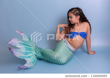 Beautiful elegant girl in a mermaid costume, isolated on a blue background. Beautiful elegant girl in a mermaid costume, isolated on a blue background. 116608995