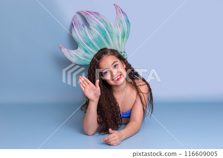 Beautiful girl in a mermaid costume, friendly, lies on a blue background 116609005