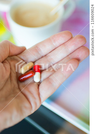 Close up of caucasian female hand with pills at breakfast 116609024