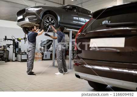 Mechanics working on car in auto repair shop Mechanics working on car in auto repair shop 116609492