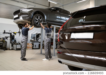 Mechanics working on car in modern auto repair shop 116609493