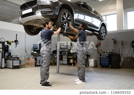 Two mechanics working on car in auto repair shop Two mechanics working on car in auto repair shop 116609502