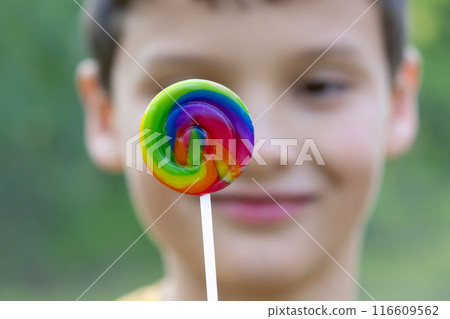 Boy is holding a bright spiral lollipop, summer vibes. Boy is holding a bright spiral lollipop, summer vibes. 116609562