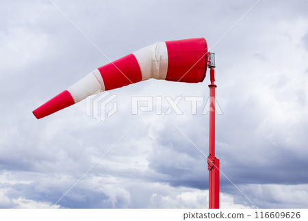 Red and white weather vane and dramatic cloudy sky. 116609626