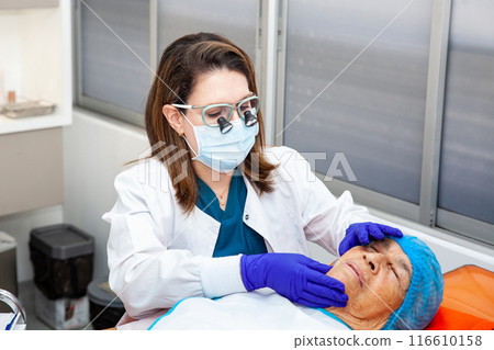 Dermatologist carrying out a skin biopsy on the face of a senior adult patient 116610158