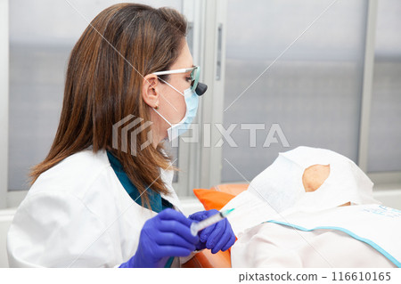 Dermatologist carrying out a skin biopsy on the face of a senior adult patient. Application of anesthesia. 116610165