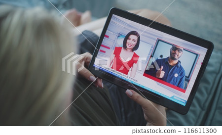 Woman watches news broadcast about US election using tablet 116611300