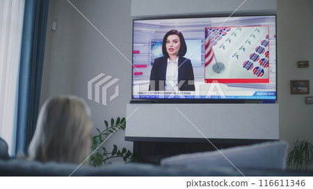 Adult woman watches TV news about elections in USA Adult woman watches TV news about elections in USA 116611346