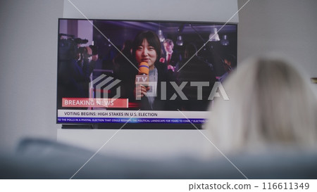 Woman rests on couch, watches breaking news on Election Day 116611349