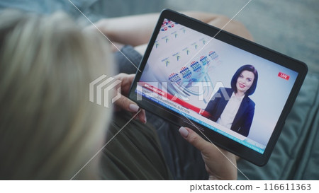 Tablet screen shows news broadcast about US elections with female newscaster 116611363