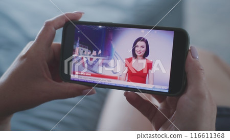 Close up of woman watching news about elections in the United States using smartphone 116611368