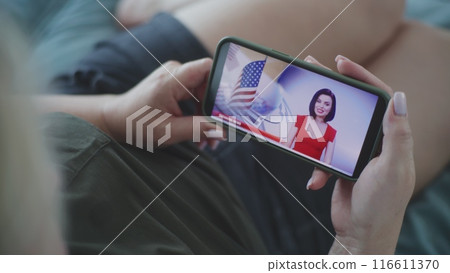 Close up of woman watching news about elections in the United States using smartphone Close up of woman watching news about elections in the United States using smartphone 116611370