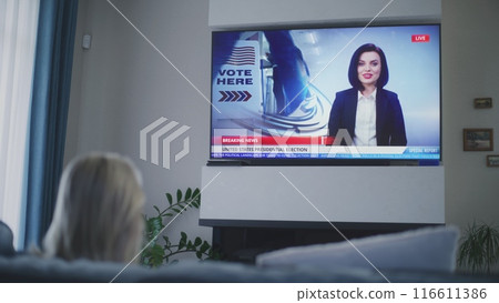 Adult woman watches TV news about elections in USA Adult woman watches TV news about elections in USA 116611386