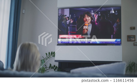 Woman rests in living room, watches live broadcast on TV 116611456