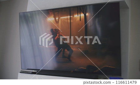 Big TV screen with displayed action movie on the wall 116611479