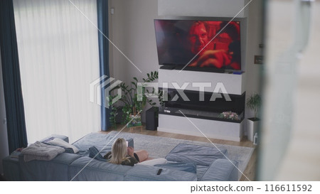 Caucasian woman rests, watches TV and uses mobile phone Caucasian woman rests, watches TV and uses mobile phone 116611592