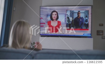 Adult woman rests on sofa in living room and watches TV news Adult woman rests on sofa in living room and watches TV news 116611595