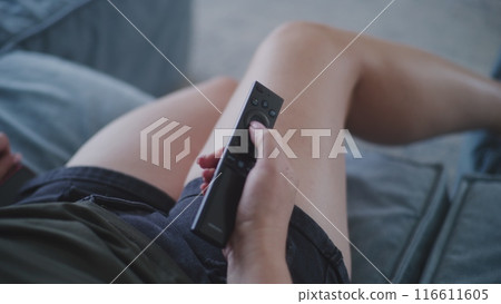 Close up of woman holding remote control for the TV in hand and using it 116611605